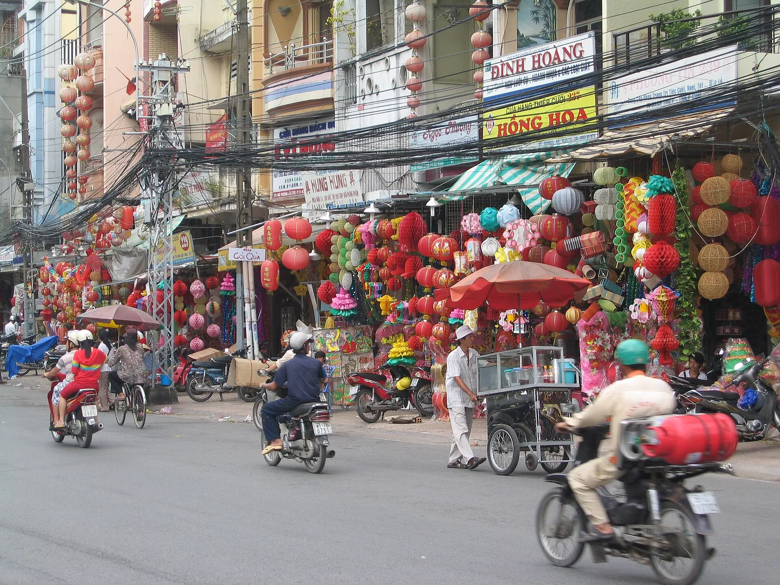 Red and yellow lanterns hanging outside shophouses on Hai Thuong Lan Ong Boulevard, with motorbikes in the street