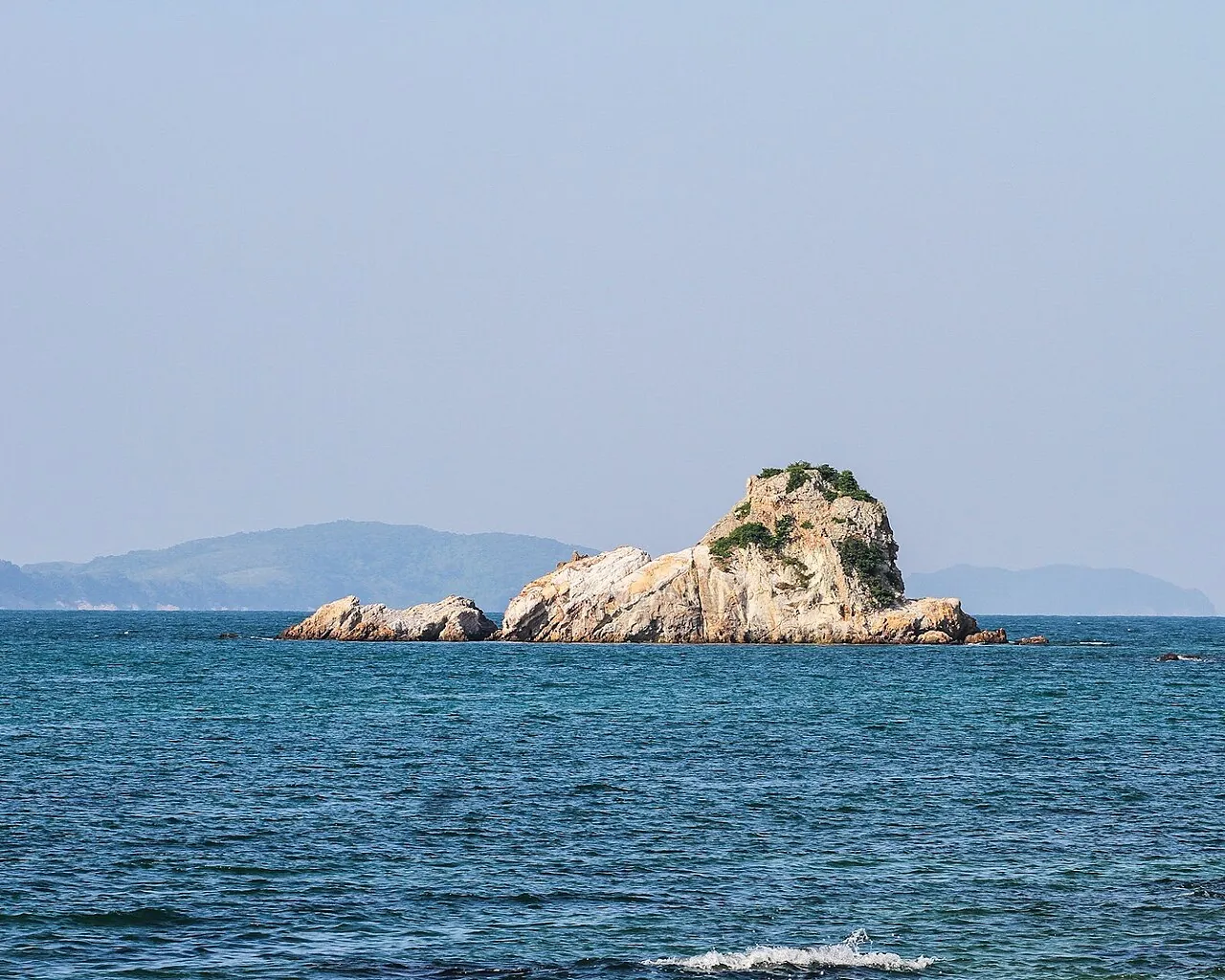 A rocky limestone islet rising from blue sea off Co To