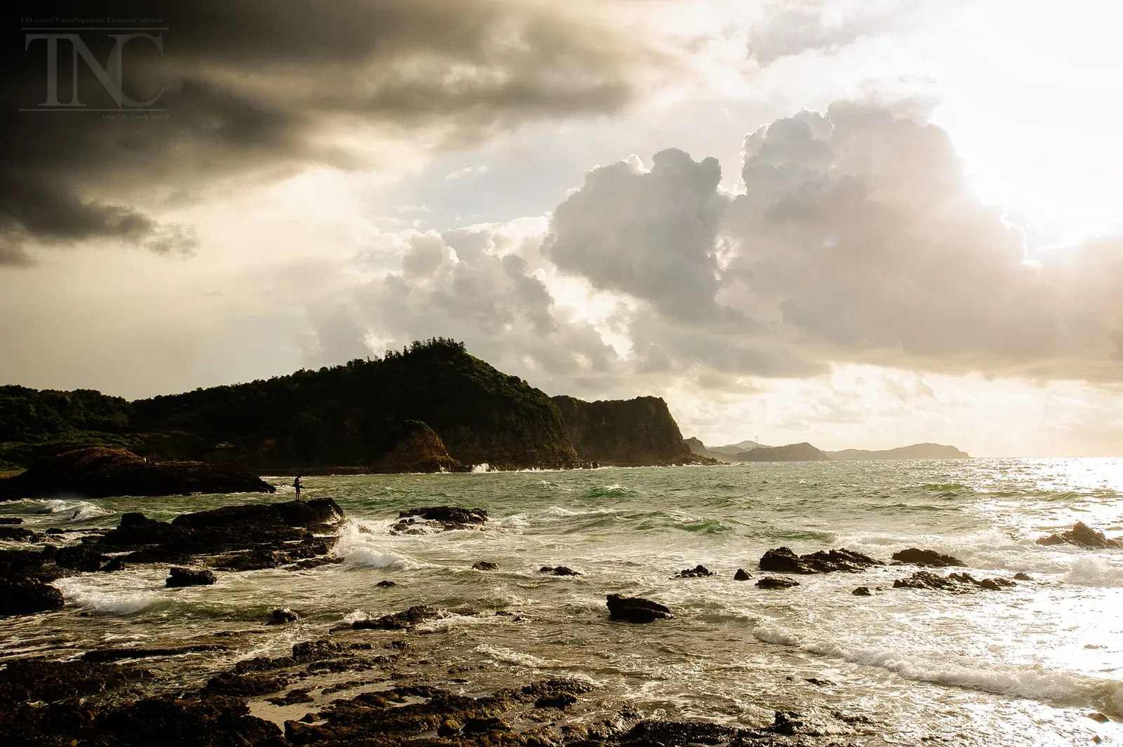 Waves breaking over a rocky shore below a forested headland under heavy clouds, Co To Island