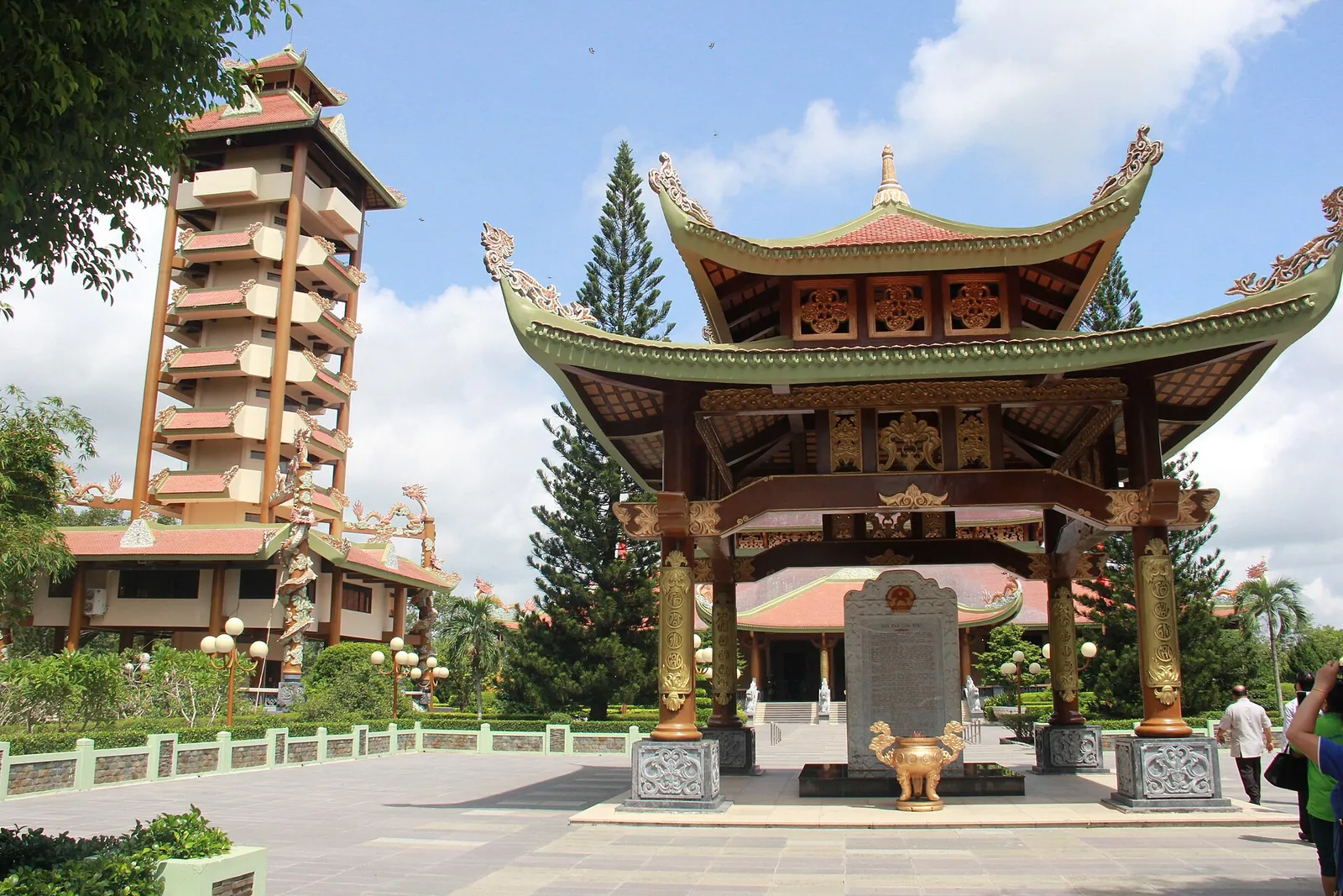 Stele house with a curved tiled roof in front of the nine-storey tower at Ben Duoc Memorial Temple
