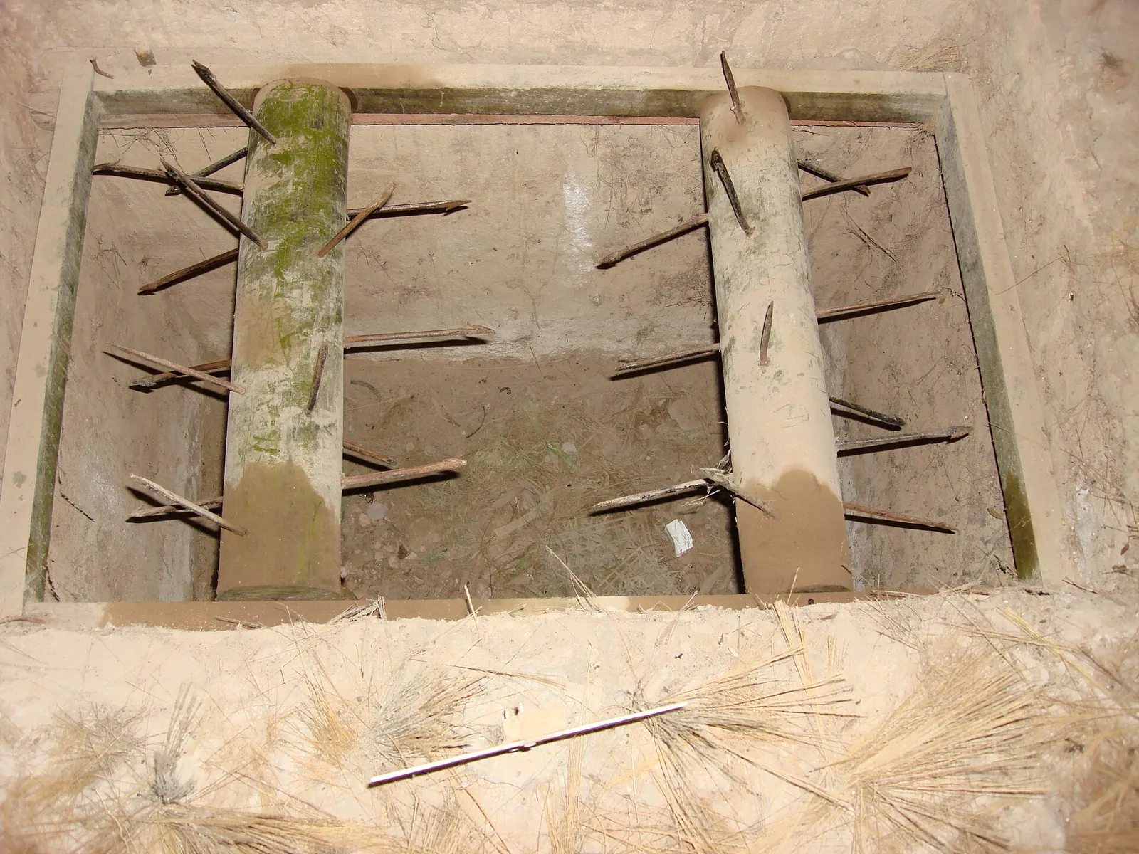 A pit lined with wooden frames and protruding iron spikes, a reconstructed booby trap at the Cu Chi Tunnels