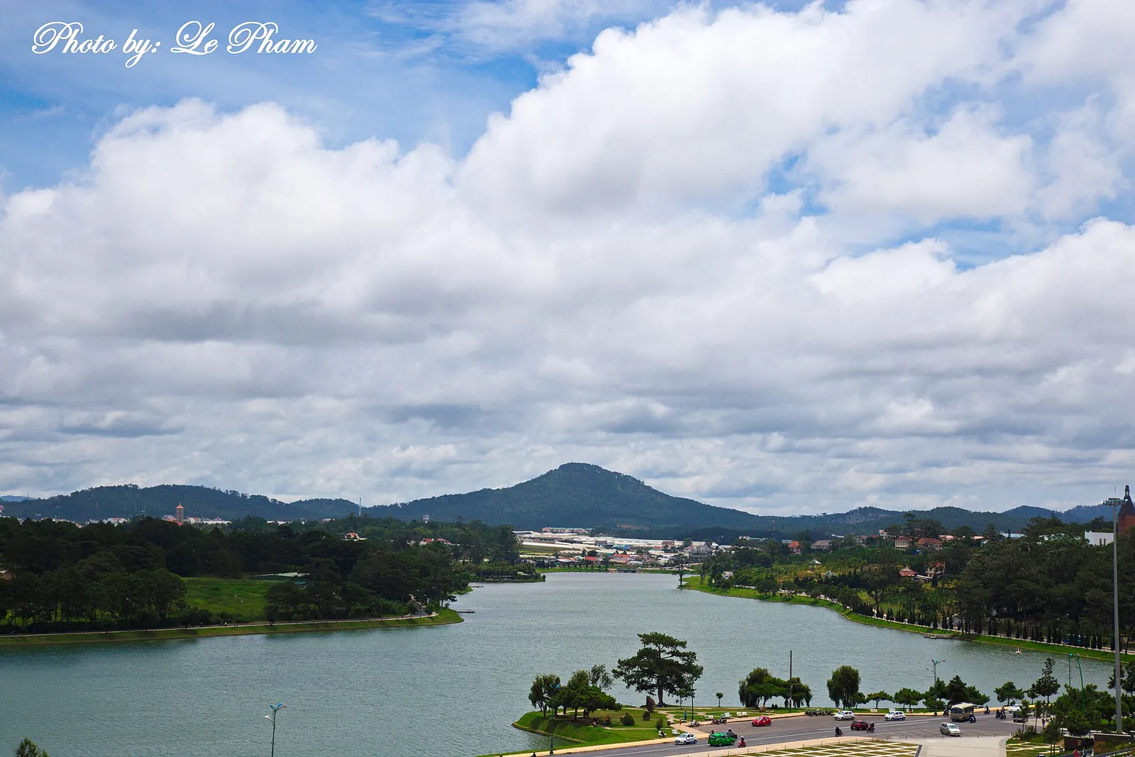 Xuan Huong Lake in Da Lat under a bright sky, with pine-covered shores and Langbiang mountain on the horizon