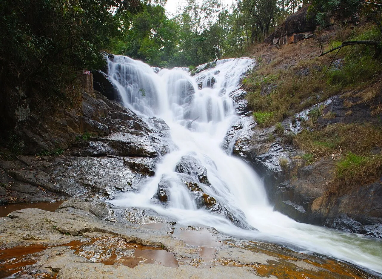 White water cascading over rock ledges at Datanla waterfall in green forest