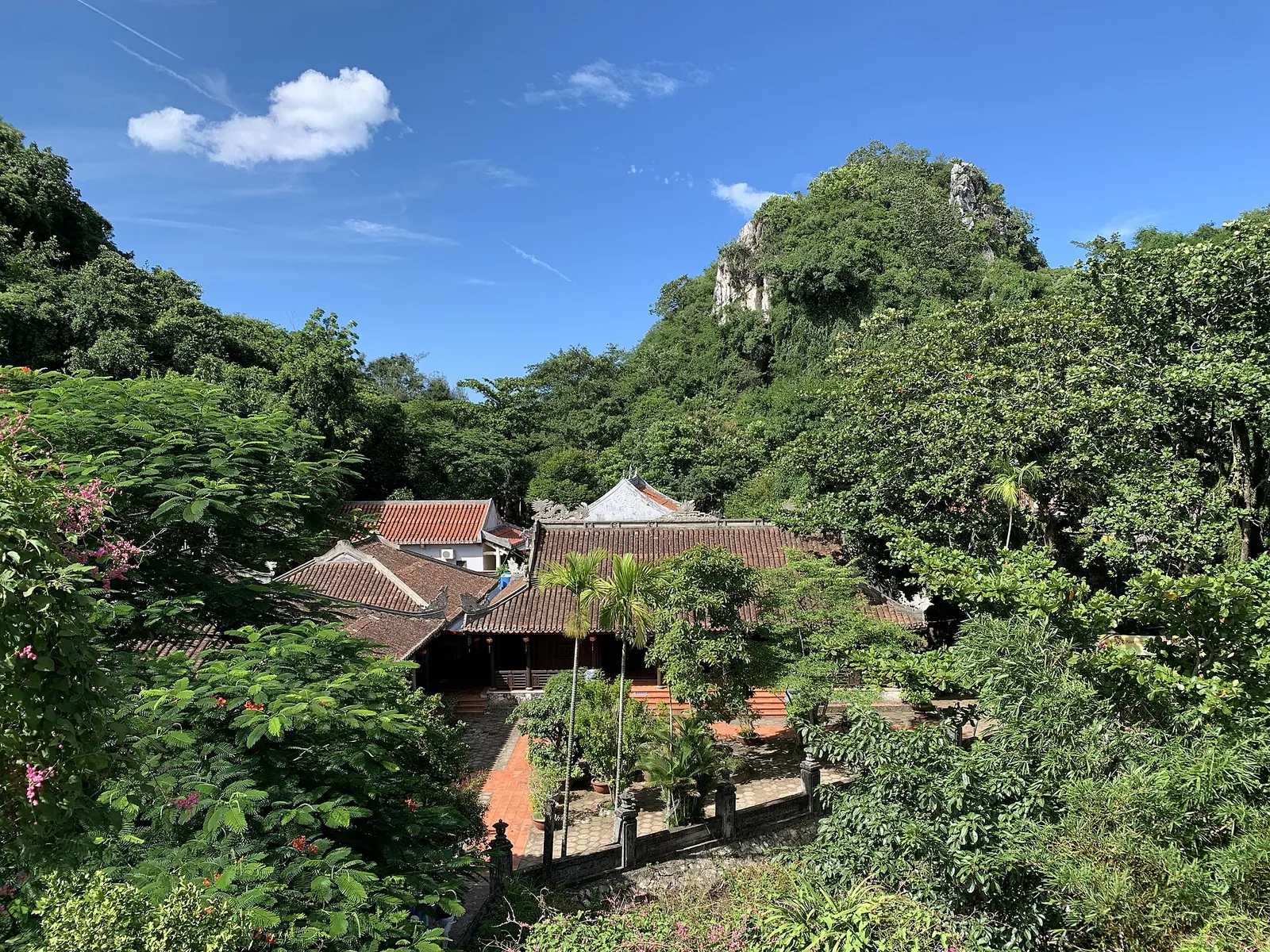 Tiled pagoda roofs among green trees below the limestone crags of Thuy Son in the Marble Mountains, Da Nang