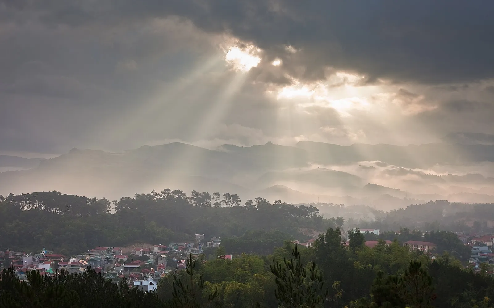 Sun rays breaking through clouds over forested hills and the Muong Thanh valley at Dien Bien Phu