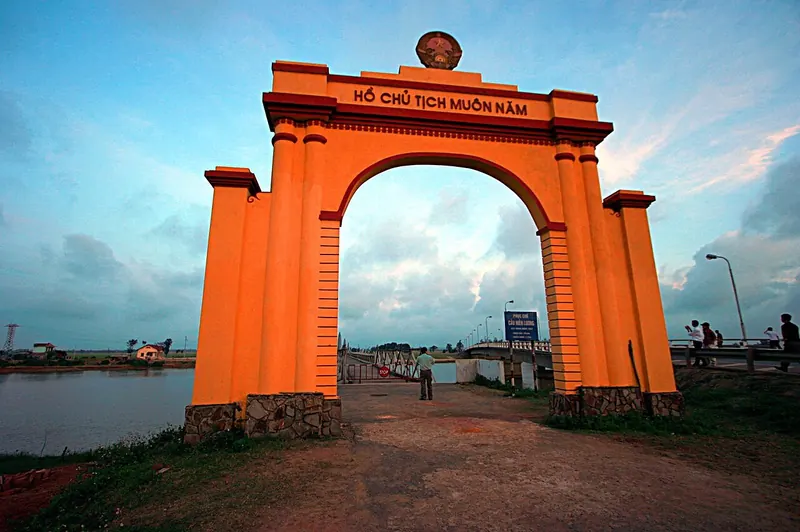 Orange memorial arch reading 'Ho Chu tich muon nam' at the Hien Luong Bridge site on the Ben Hai River
