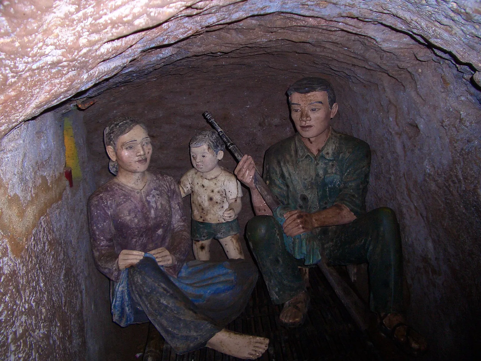 Figures of a family with a small child in a cramped family compartment carved into the clay of the Vinh Moc tunnels