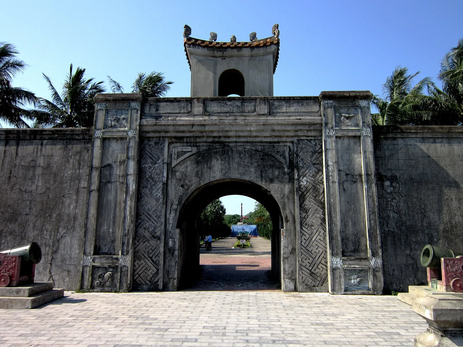 Stone gate of the Quang Tri Citadel with a small watchtower on top under a blue sky