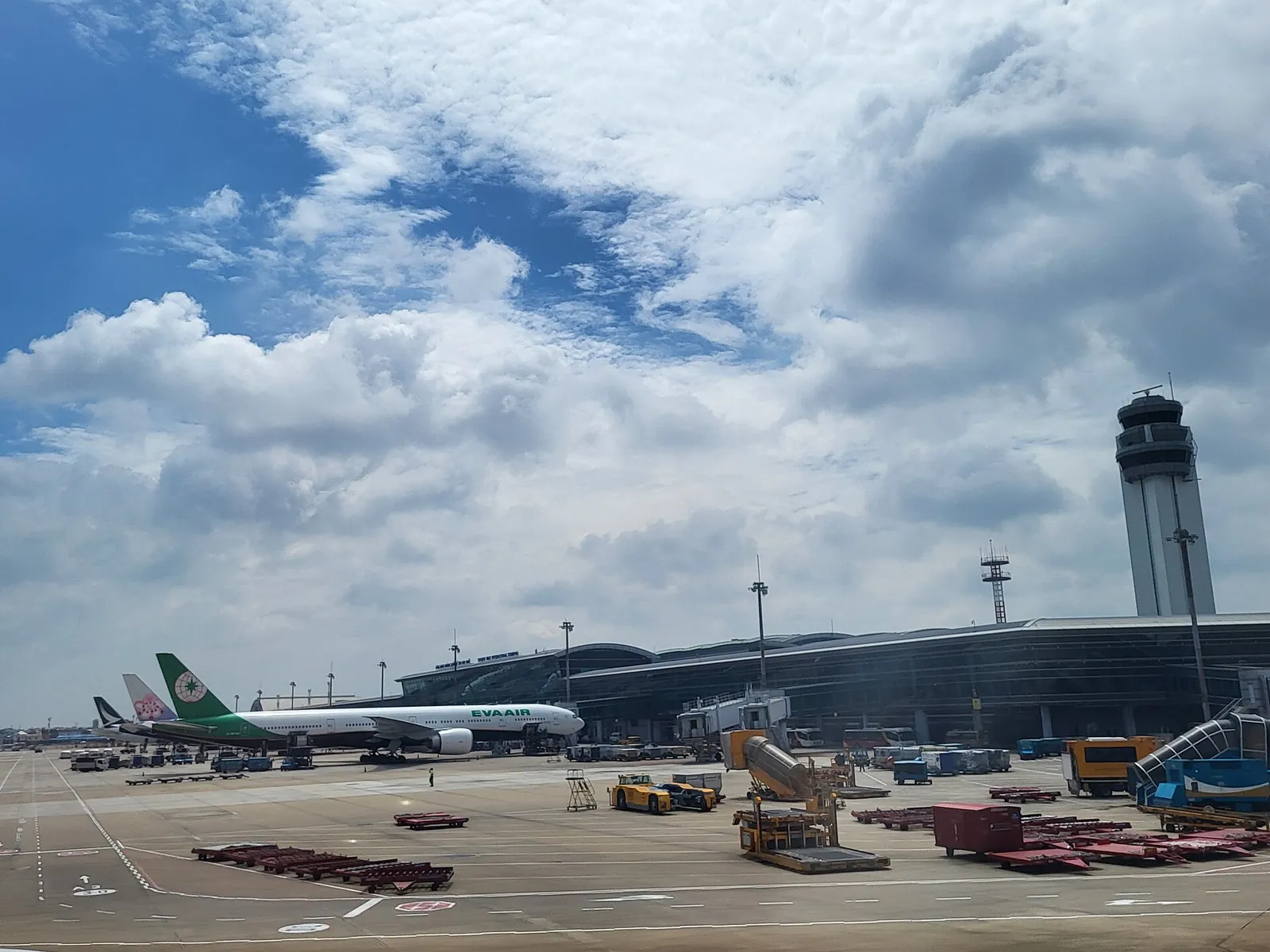 International terminal T2 of Tan Son Nhat International Airport in Ho Chi Minh City seen from the apron under a blue sky, with parked aircraft and the control tower