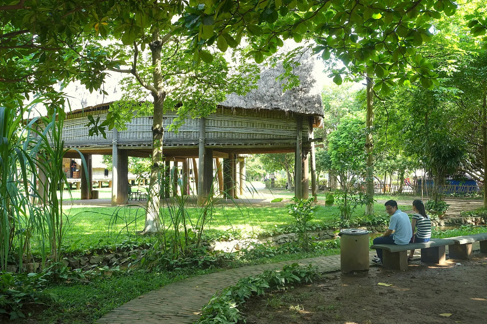 A traditional stilt house among trees in the outdoor garden of the Vietnam Museum of Ethnology, Hanoi