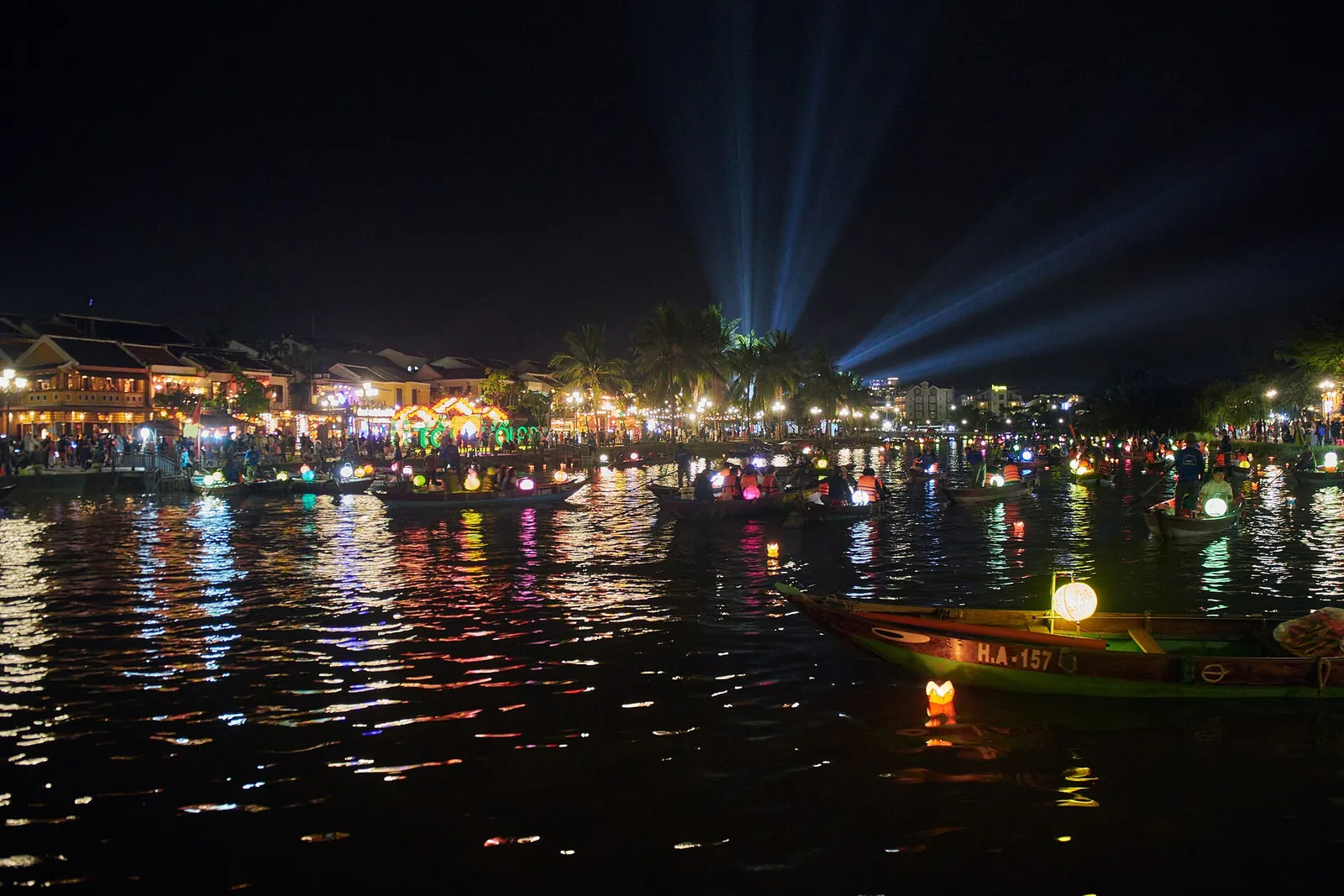 Lit boats and lantern reflections on the Thu Bon River beside Hoi An's Ancient Town at night