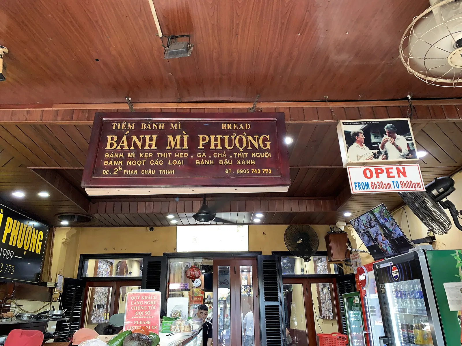 Inside Bánh Mì Phượng in Hoi An, with the red shop sign above the counter
