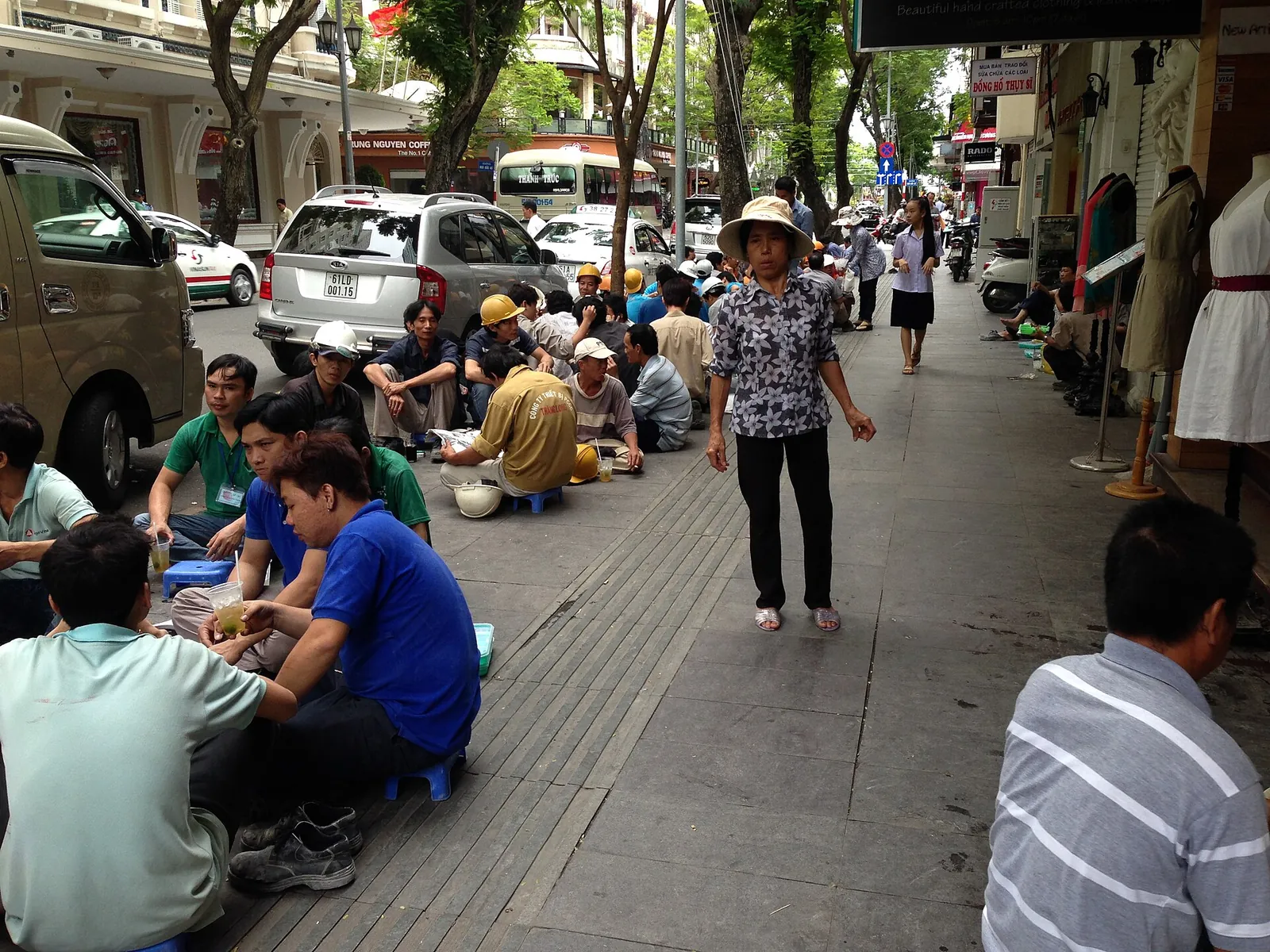 Office workers eating lunch on low stools along a pavement in Ho Chi Minh City