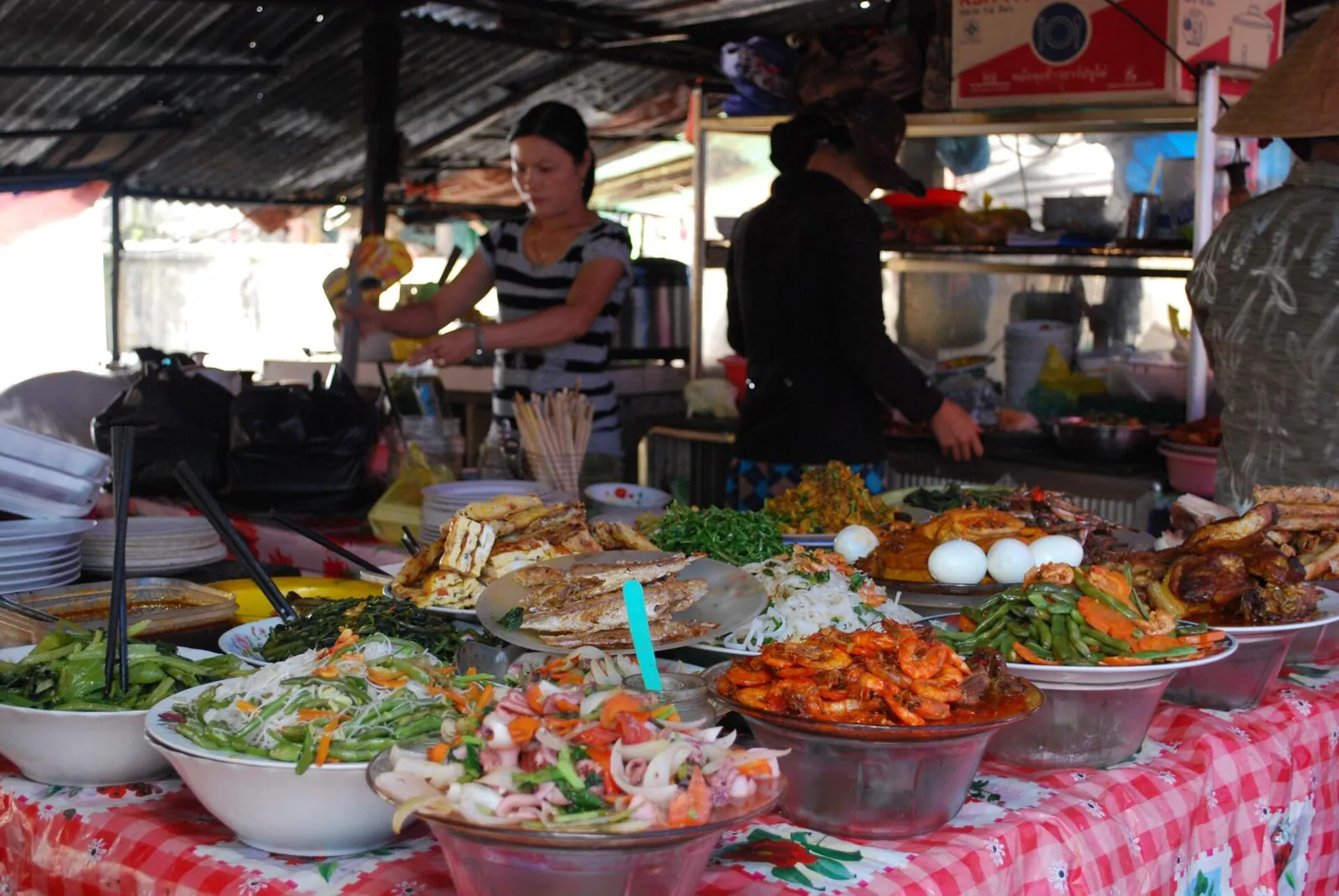 A market food stall in Hoi An with bowls of prepared dishes laid out on a checked tablecloth