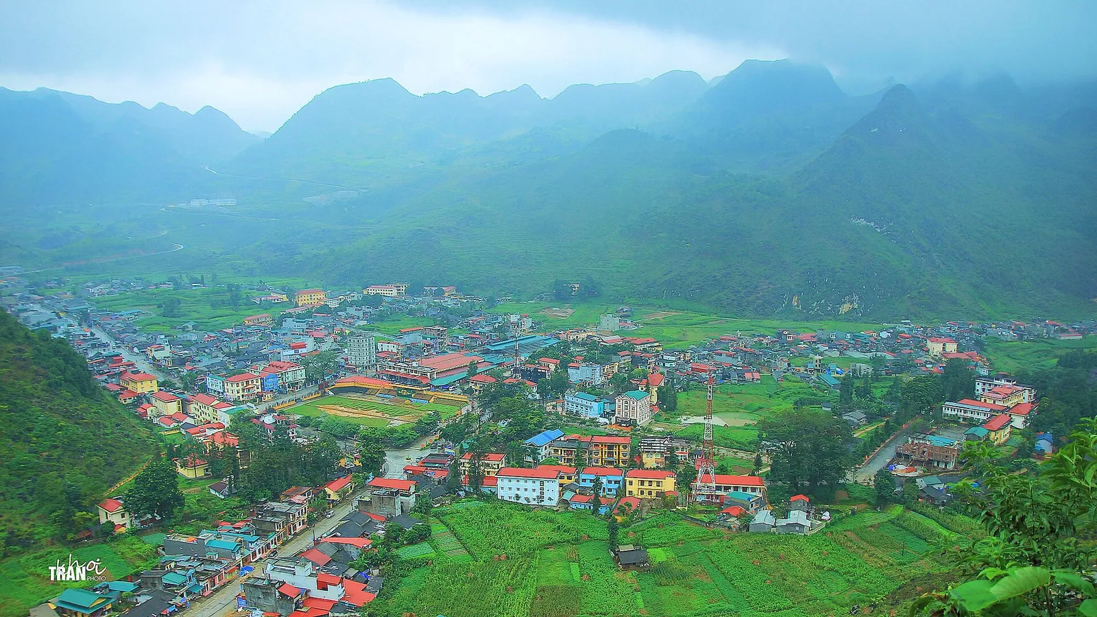 Meo Vac town in a green valley ringed by limestone mountains, seen from a viewpoint above