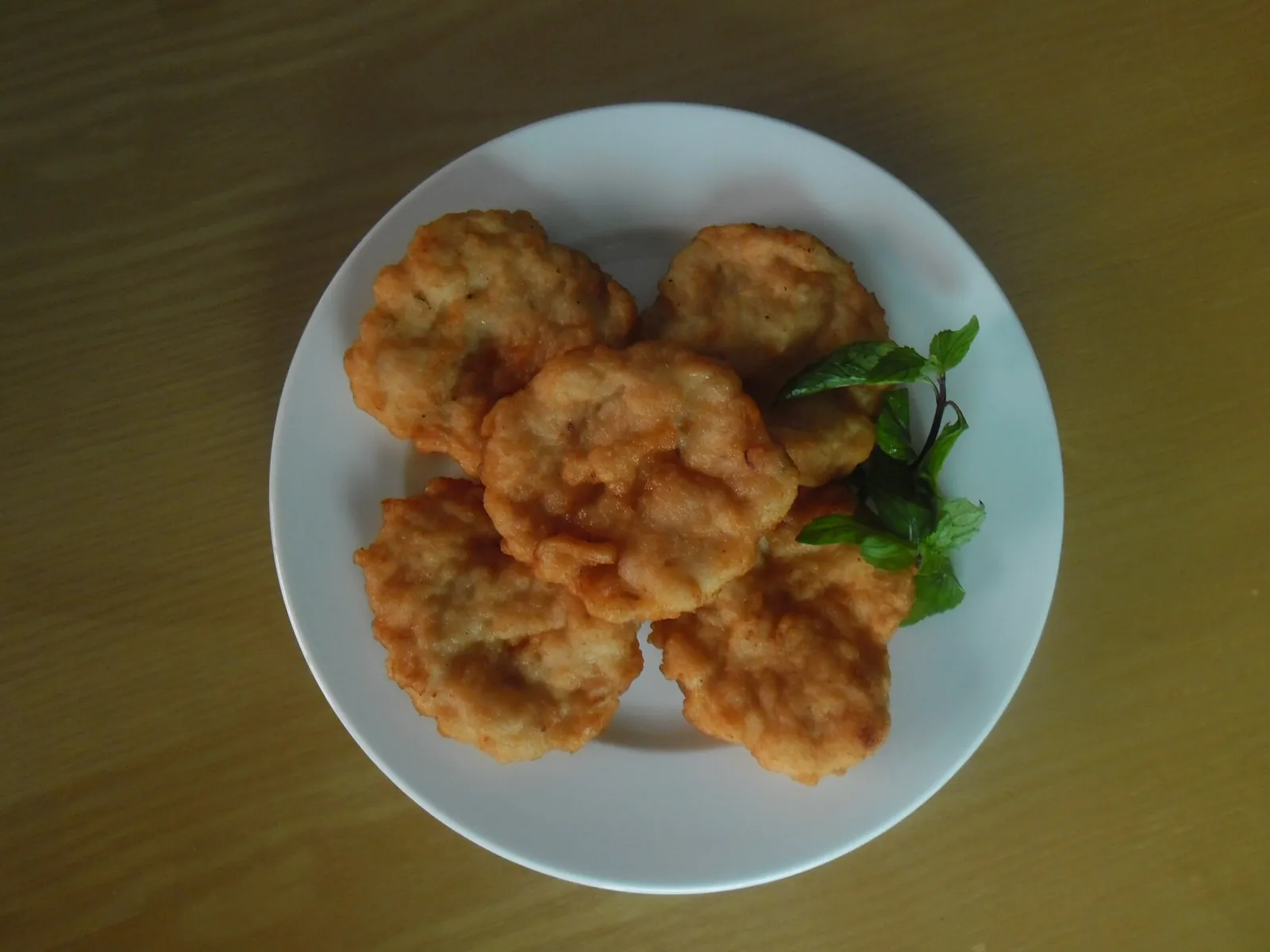 A plate of golden fried squid cakes (cha muc) garnished with herbs