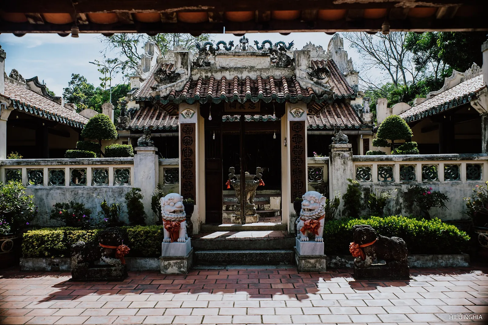 Tiled-roof temple of the Mac family with stone lions and a paved courtyard in Ha Tien