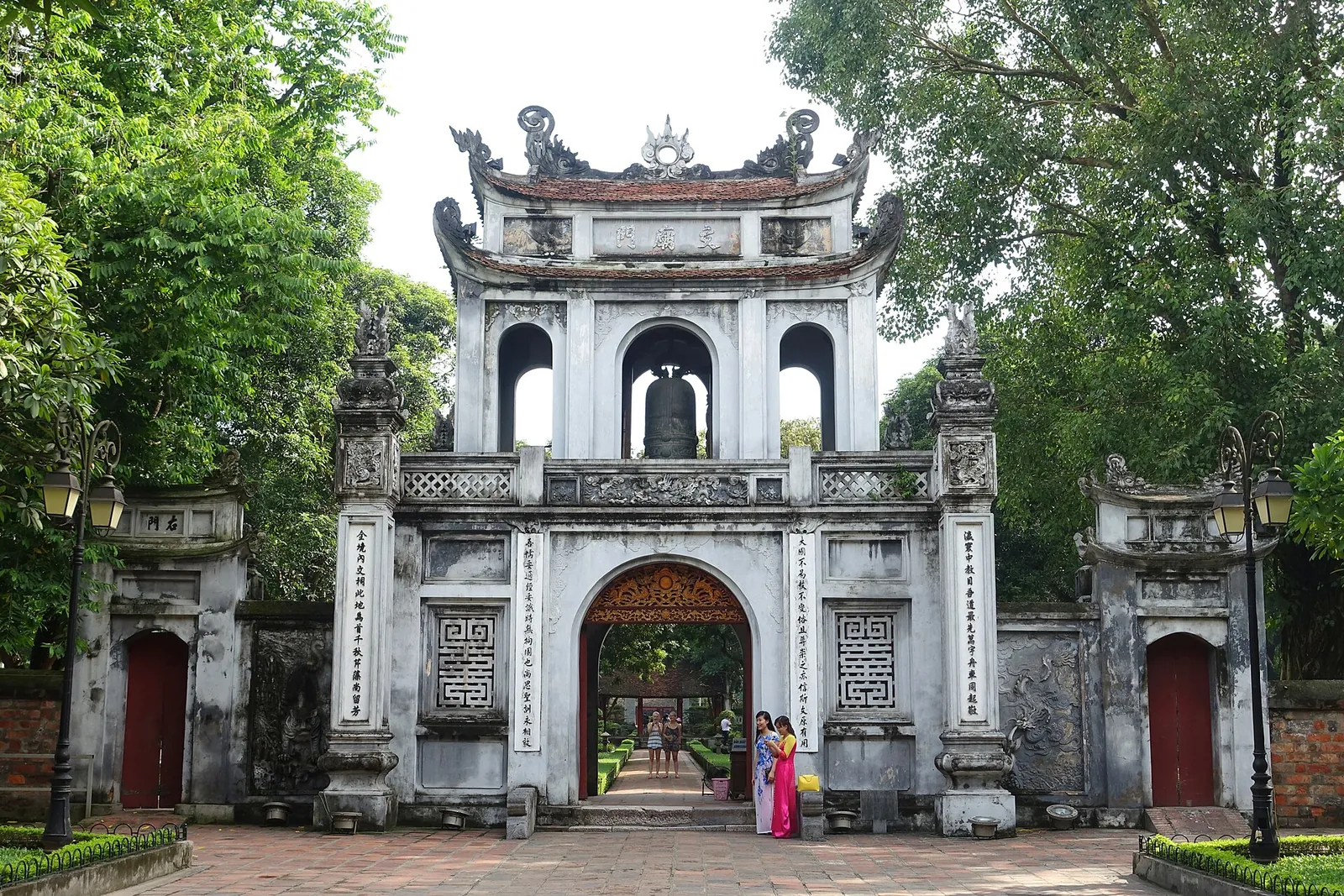 Ornate triple-arched main gate of the Temple of Literature in Hanoi, framed by trees