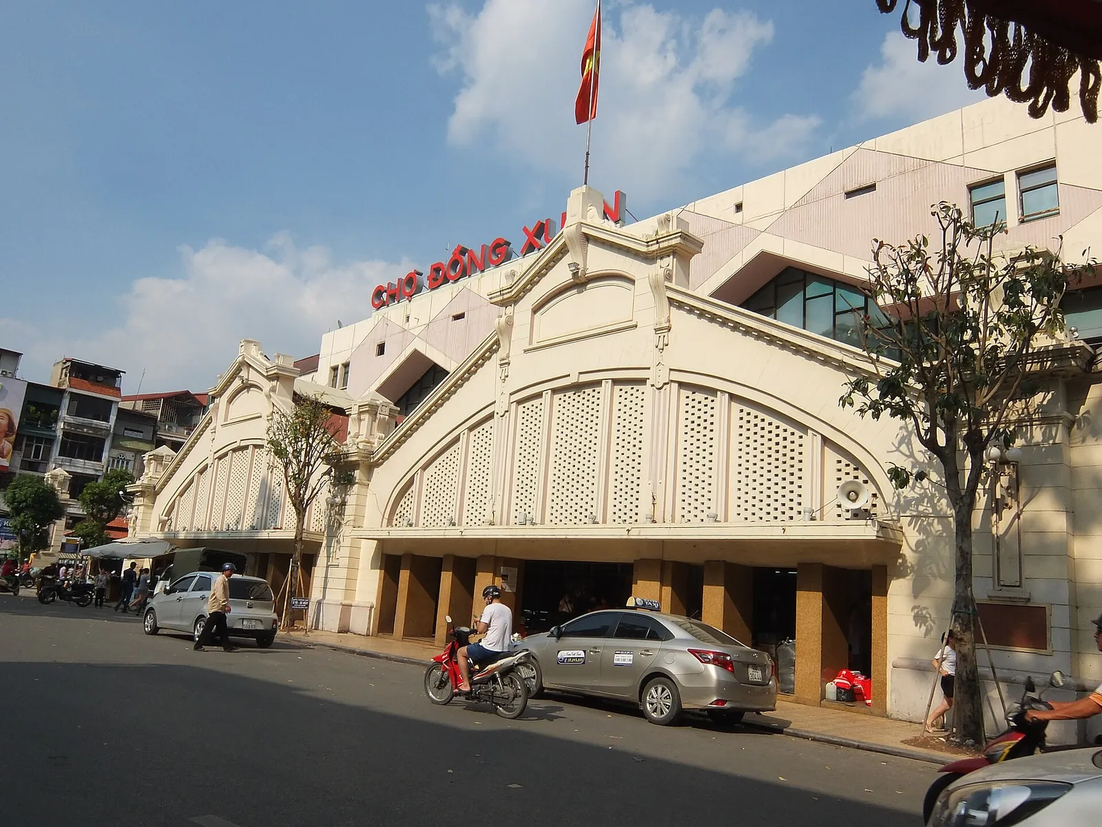 The arched facade of Dong Xuan Market under a blue sky in Hanoi's Old Quarter