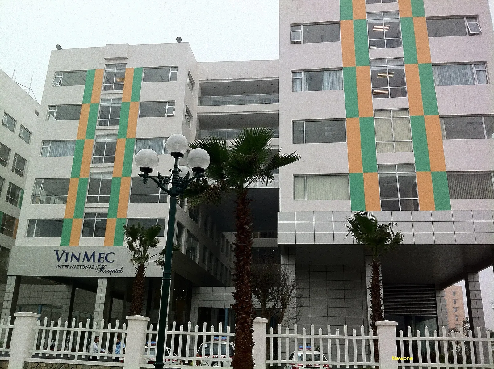 The striped facade of Vinmec International Hospital at Times City in Hanoi, with palm trees at the gate
