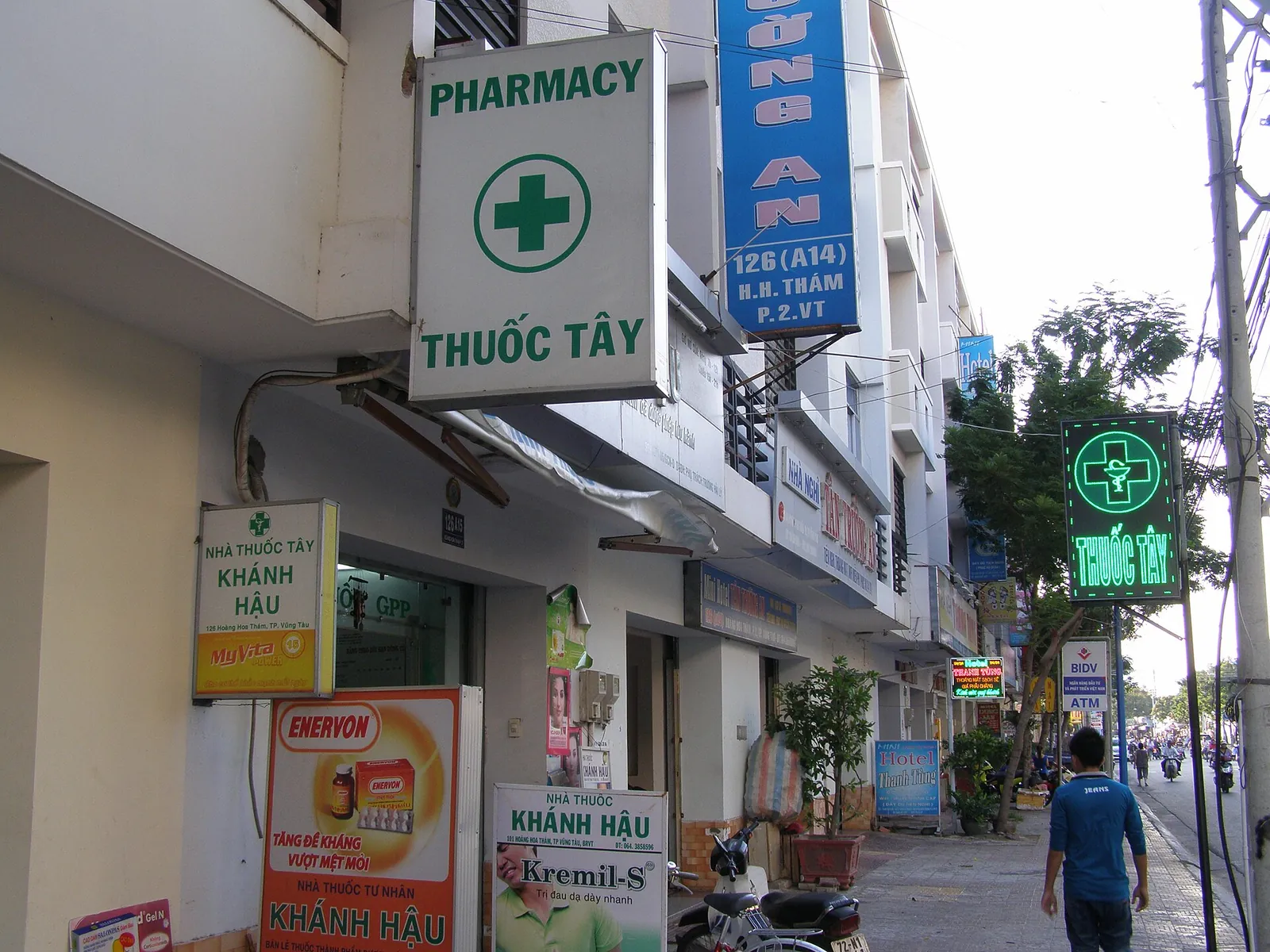 A row of pharmacies with green cross signs and Thuoc Tay lettering on a street in Vung Tau