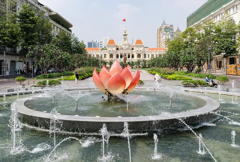Lotus-shaped fountain on Nguyen Hue boulevard with the cream-and-white City Hall building behind it, Ho Chi Minh City