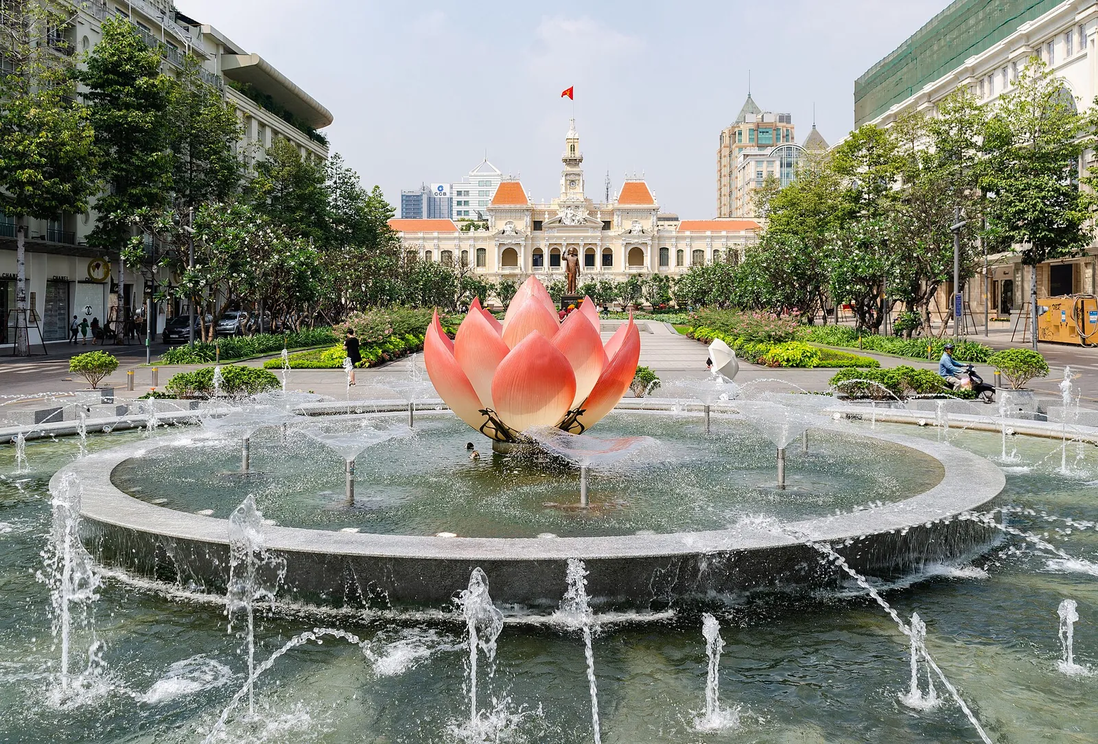 Lotus-shaped fountain on Nguyen Hue boulevard with the cream-and-white City Hall building behind it, Ho Chi Minh City