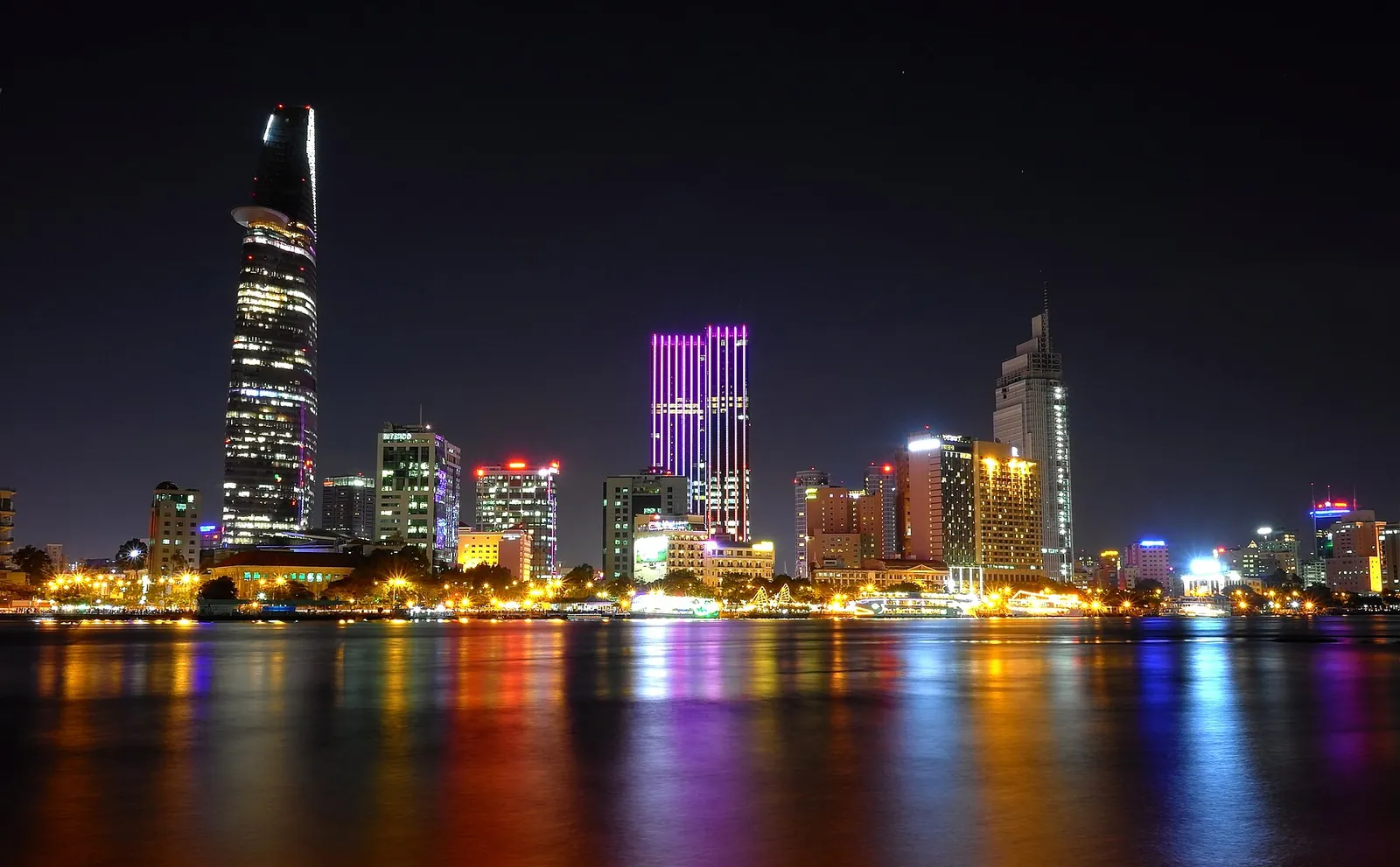 The Ho Chi Minh City skyline lit up at night and reflected in the Saigon River