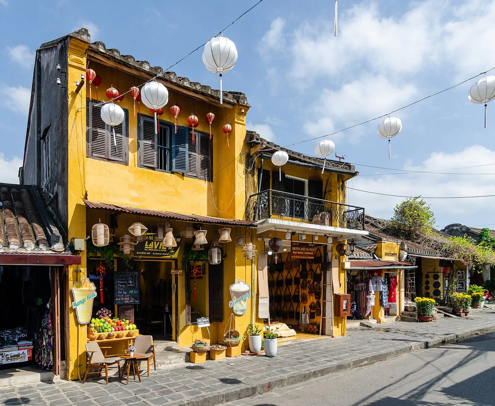 Yellow two-storey shophouses hung with white lanterns on a street in Hoi An's Old Town