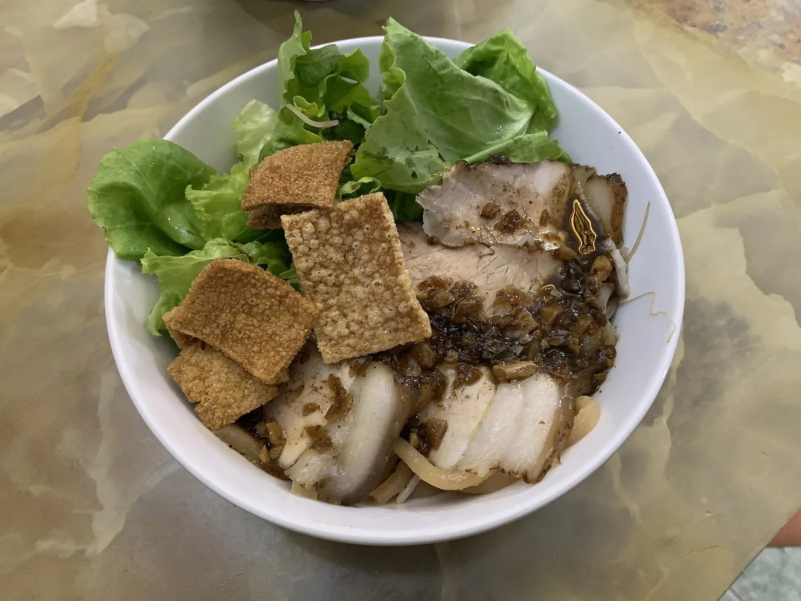A bowl of cao lầu in Hoi An: thick noodles with sliced pork, crisp crackers and fresh greens