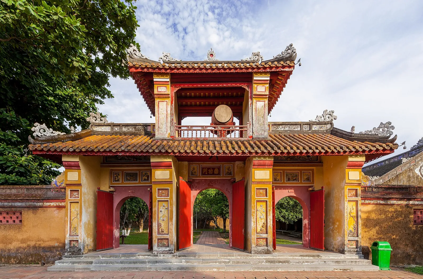 A red and gold gate with a tiled roof inside the Hue Imperial City, framed by ochre walls