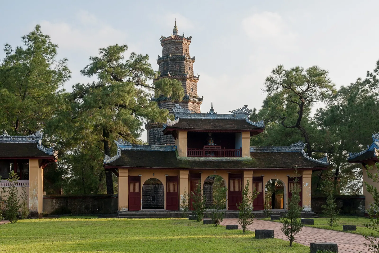 The seven-tiered tower of Thien Mu Pagoda rising behind a temple gate and lawn