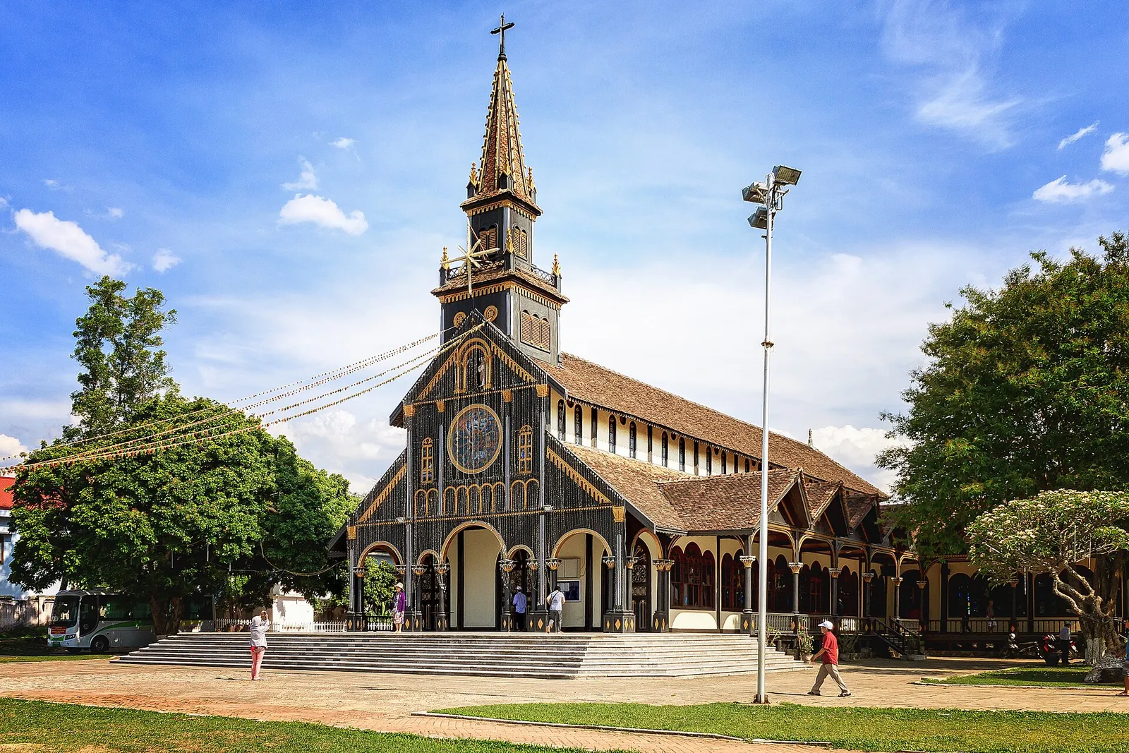 The wooden Kon Tum Cathedral with its tall cross tower and dark timber walls under a blue sky