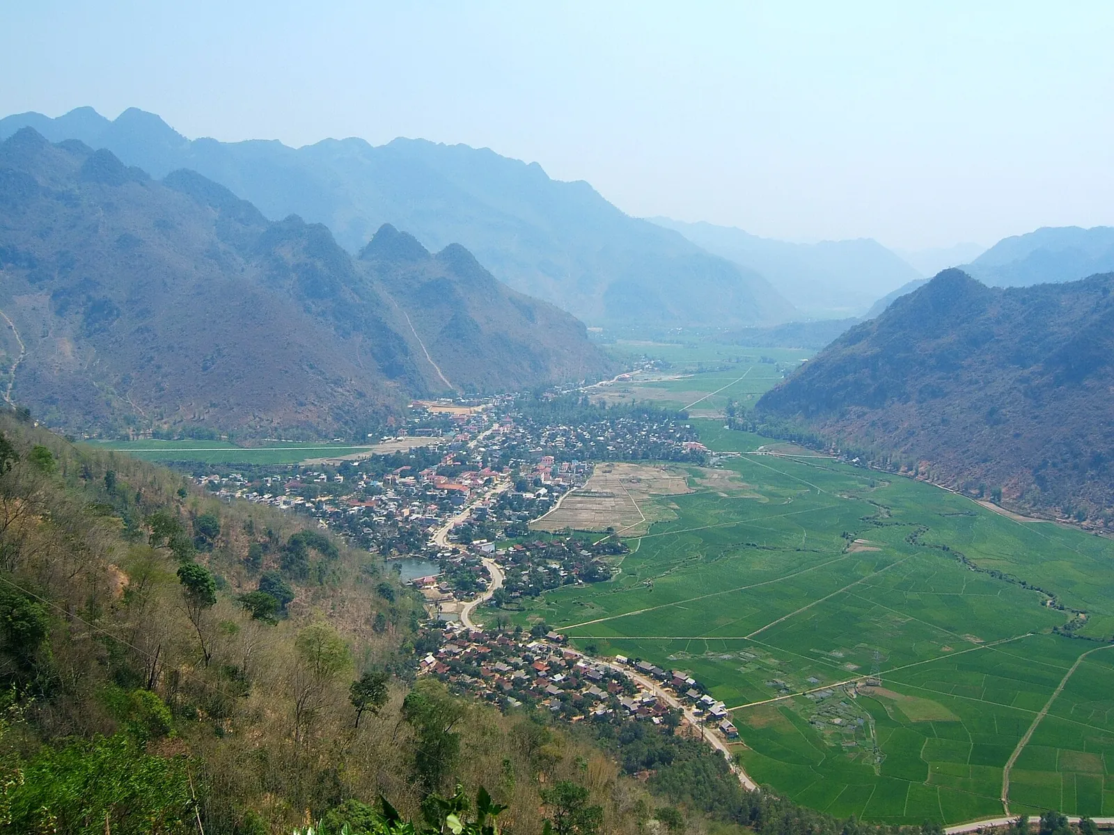 View from the mountain road down into the Mai Chau valley, with villages and green rice fields between ridges