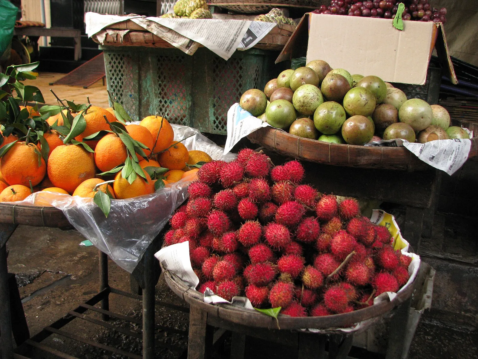 Baskets of rambutans, oranges and other fruit at a market stall in Chau Doc