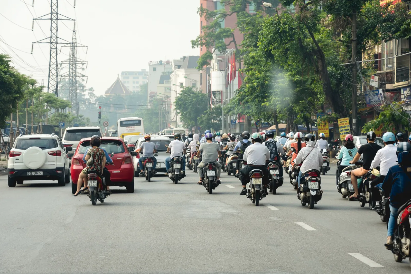 Dozens of motorbikes and a few cars filling a wide street in Hanoi