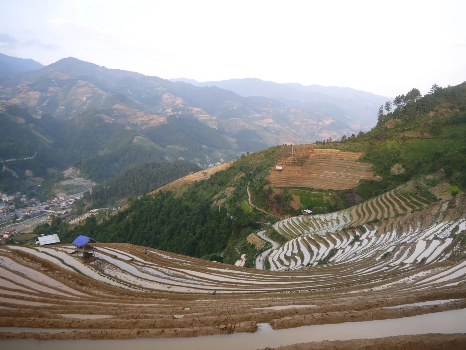 Flooded rice terraces reflecting the sky in De Xu Phinh, Mu Cang Chai, with mountains behind