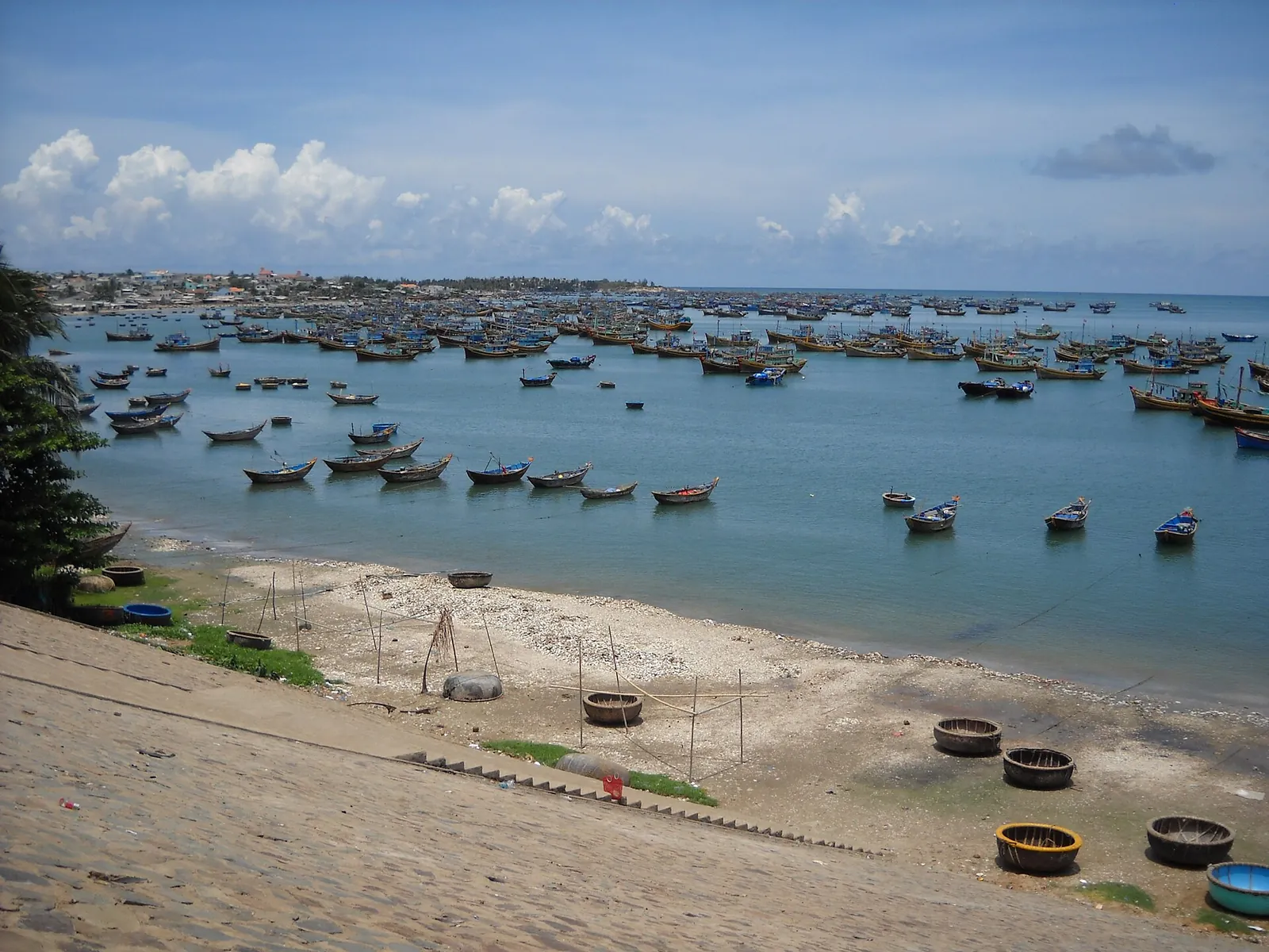 Colourful fishing boats and round basket boats moored in the bay at the Mui Ne fishing village