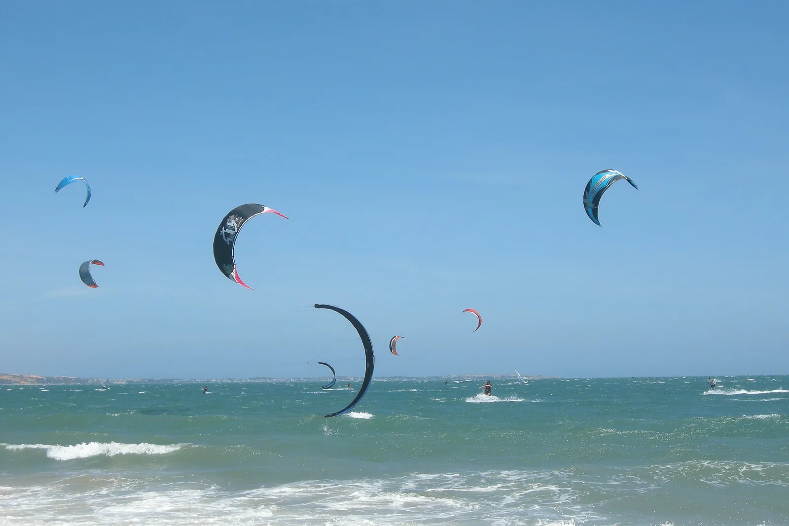 Kitesurfers' kites in the air over the waves off Mui Ne beach