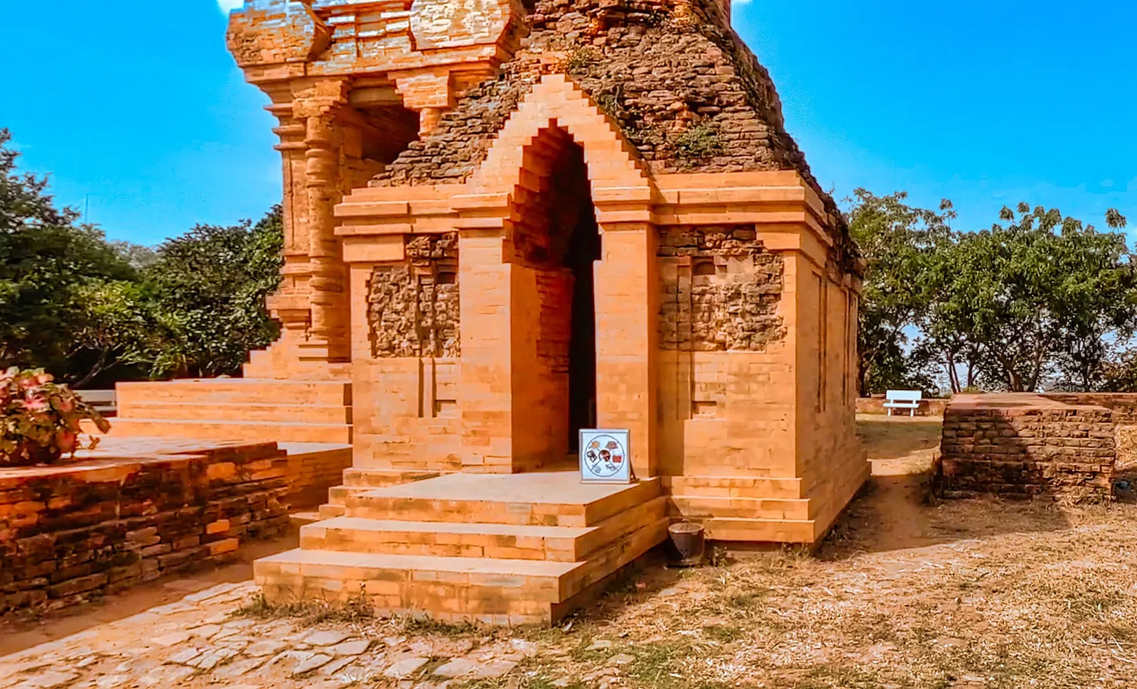 A red-brick Cham temple tower with an arched doorway at the Po Sah Inu complex under a blue sky