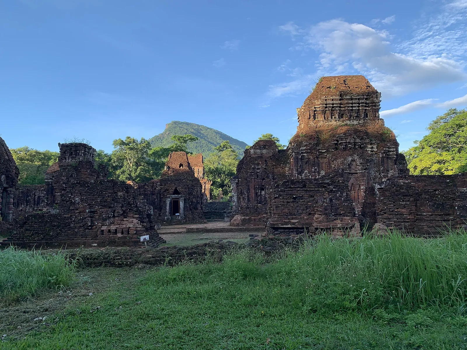 Ruined brick towers of Groups B, C and D at My Son with a forested mountain behind