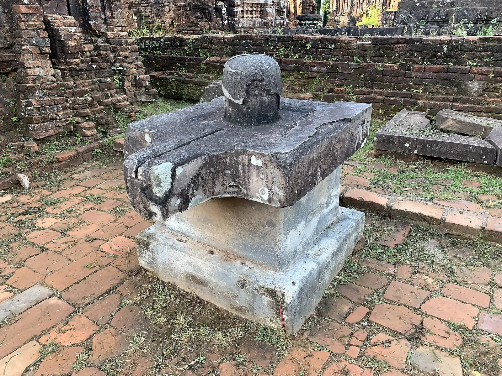 Stone linga-yoni pedestal standing on a brick floor among the ruins at My Son