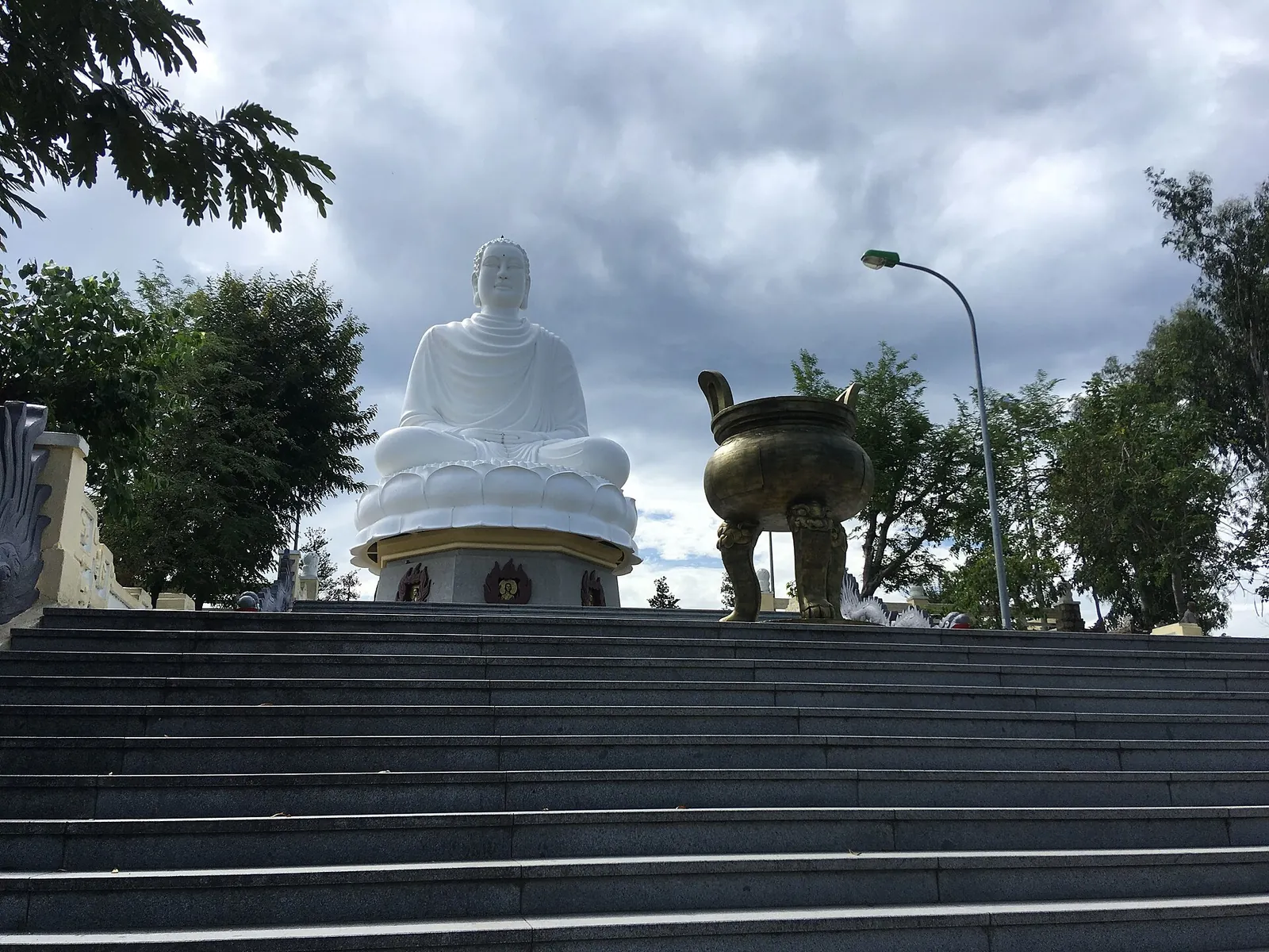 Large white seated Buddha statue at the top of a flight of steps at Long Son Pagoda, Nha Trang