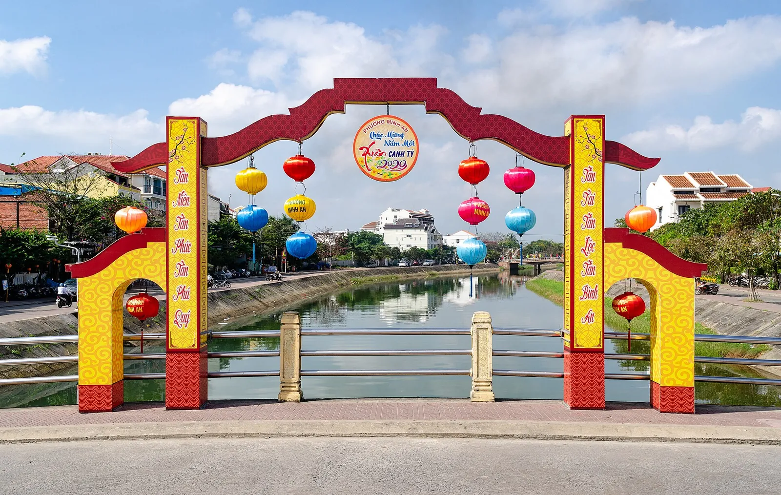 Red and yellow Tet gate with lanterns on a bridge over the Thu Bon River in Hoi An