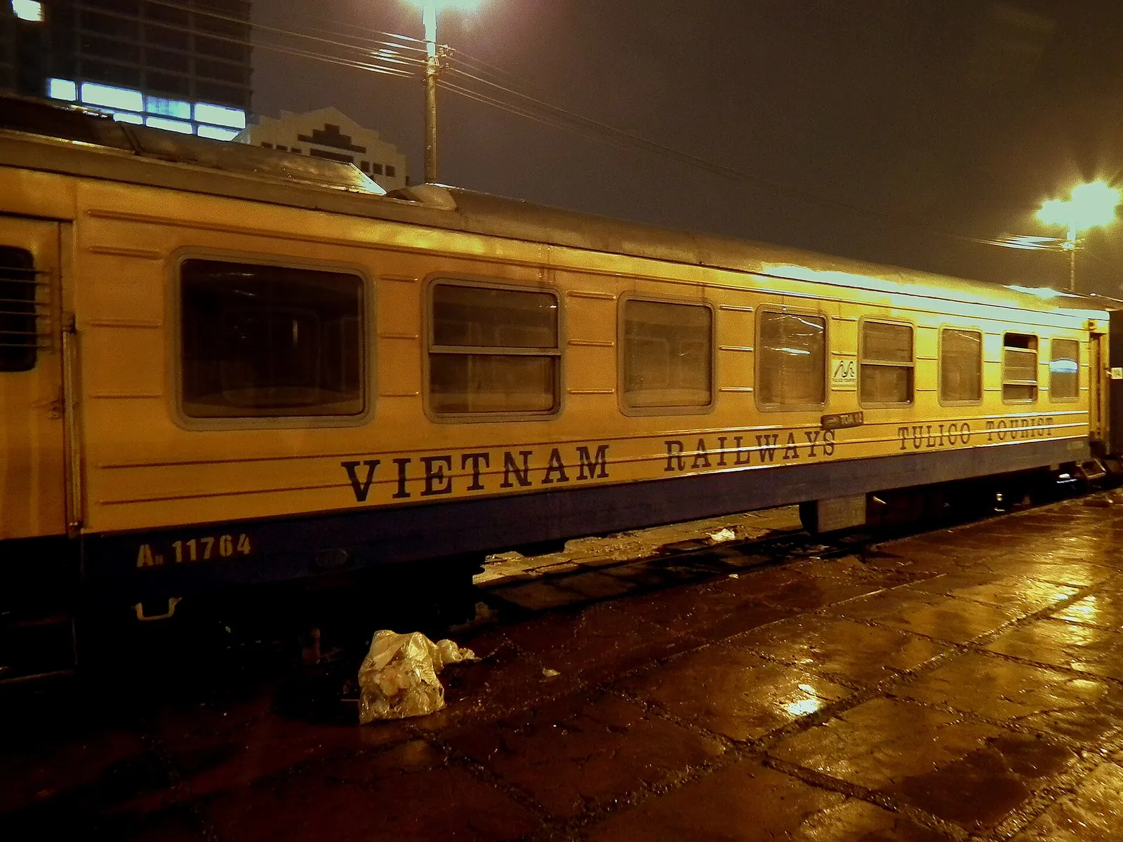 A Vietnam Railways sleeper carriage standing at a platform at night