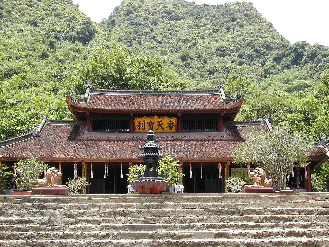 Thien Tru Pagoda with its curved tiled roofs below green limestone hills at the Perfume Pagoda