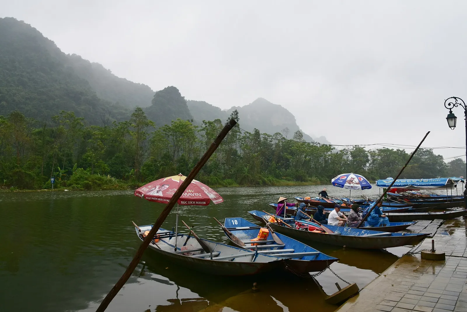 Small rowing boats moored at the wharf on Yen stream under misty limestone peaks