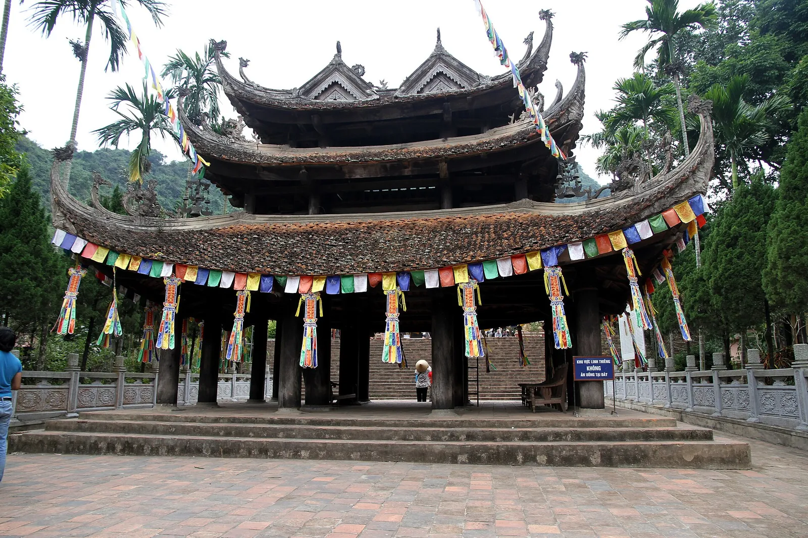 A multi-tiered pagoda pavilion hung with Buddhist prayer flags in the Perfume Pagoda complex