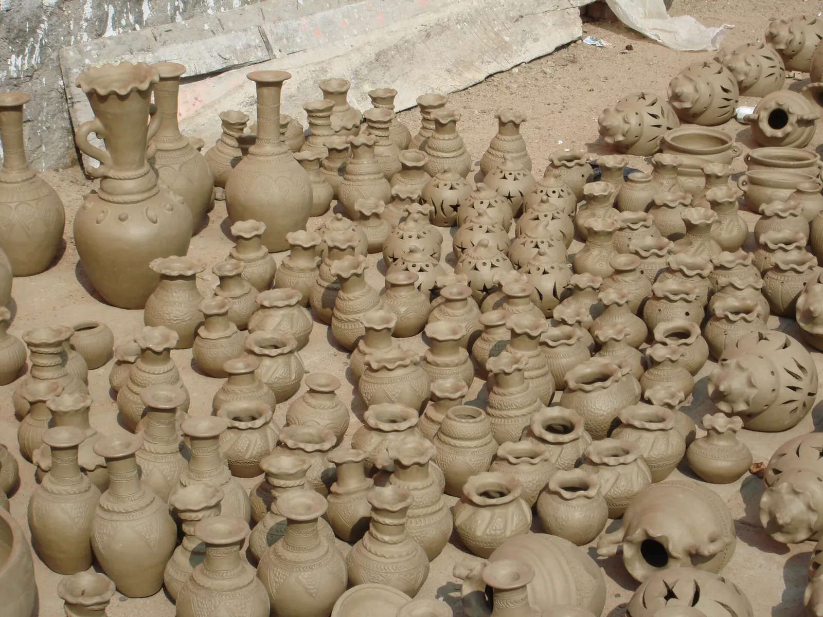 Rows of unfired, hand-shaped clay jars and vases drying on the ground at Bau Truc