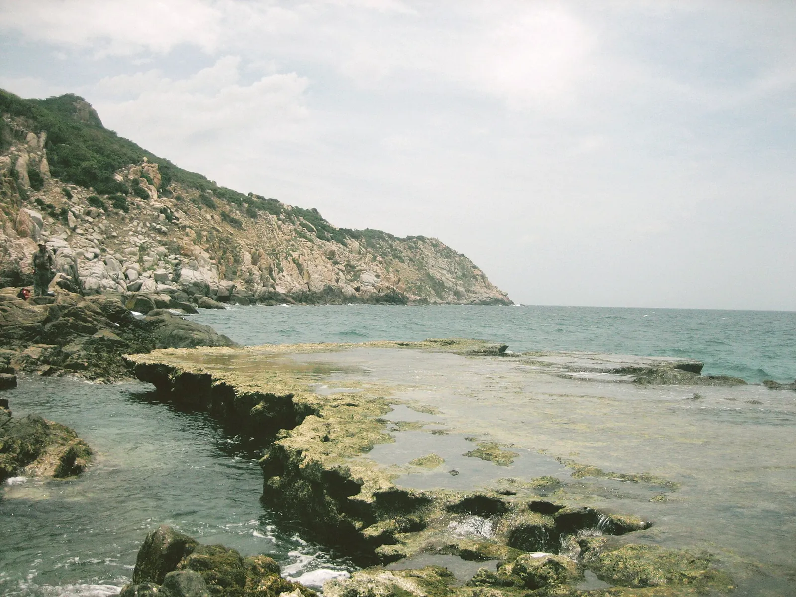 Flat shelves of old coral rock and a rocky headland at the sea edge at Hang Rai